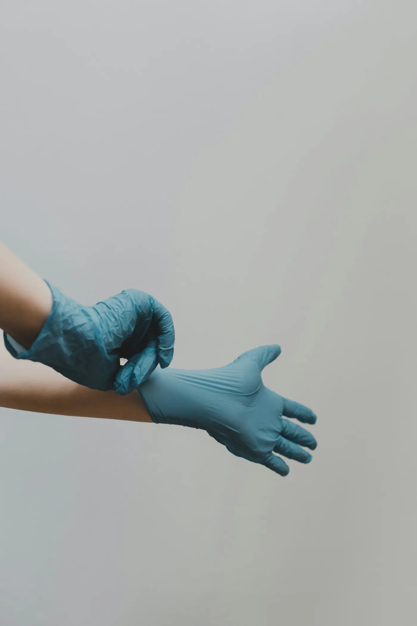 Hands pulling on blue medical gloves