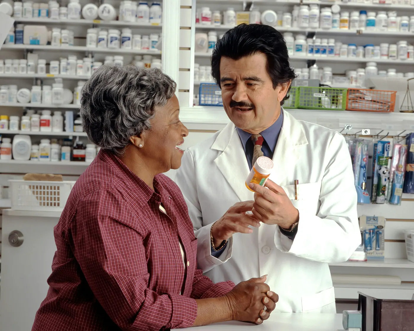 Pharmacist holding a prescription bottle at the pharmacy counter